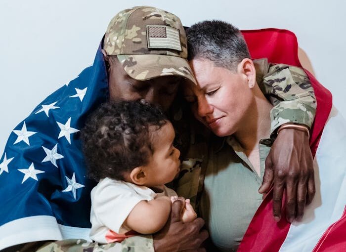 Army Couple Wrapped with an American Flag Sitting Beside Their Son